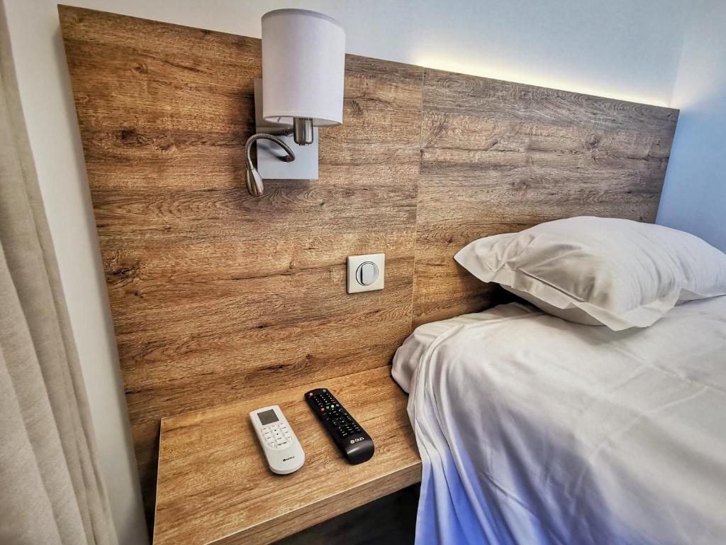 ein Bett mit zwei Fernbedienungen an einer Holzwand in der Unterkunft Ustaria in Peri