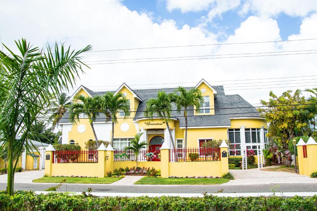 a yellow house with palm trees in front of it at Brownstone Guesthouses in Nassau