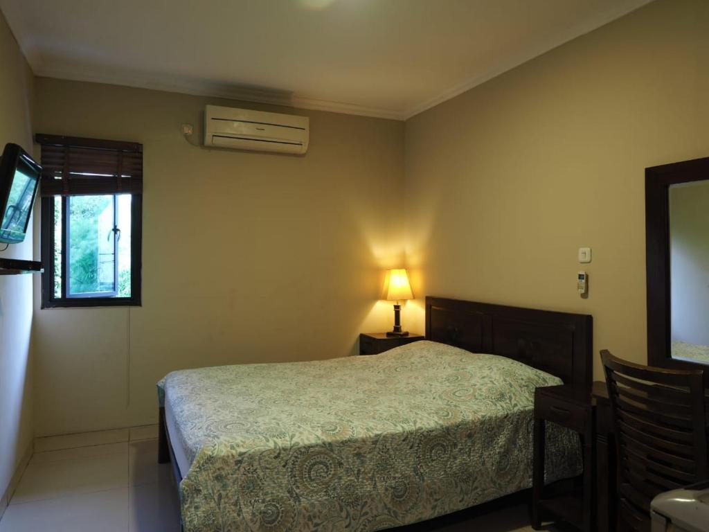 a bedroom with a bed and a lamp and a window at Rhiz Guest House Tebet in Jakarta