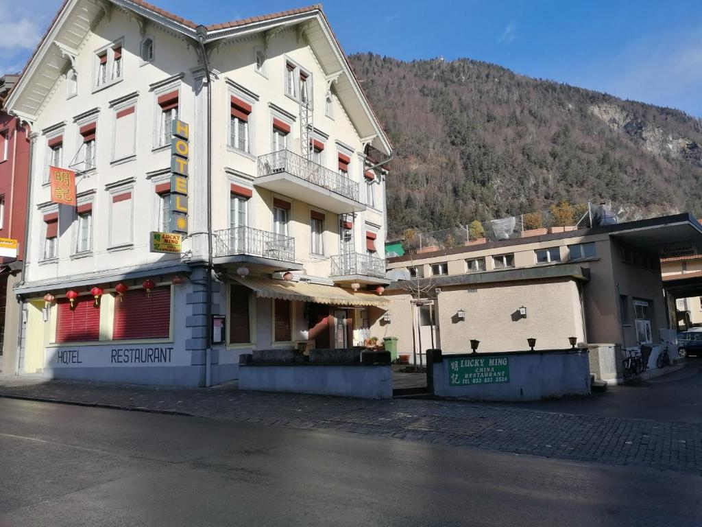 un grand bâtiment blanc sur le côté d'une rue dans l'établissement Sonne Holiday Rooms, à Unterseen