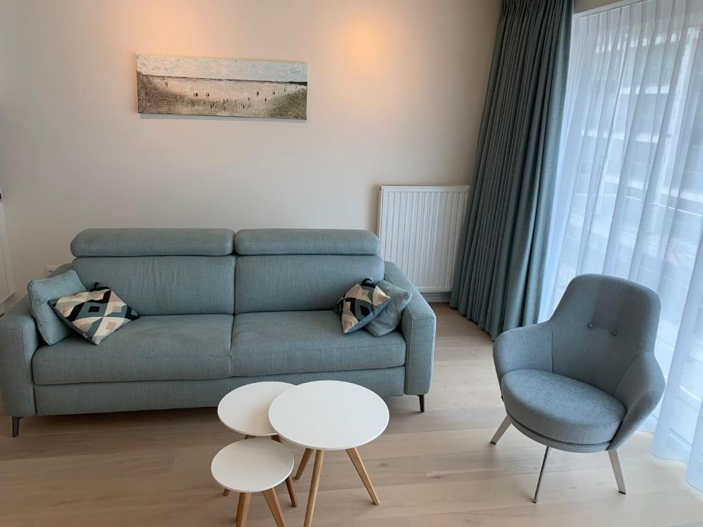 un soggiorno con divano blu e sedia di Pluk de dag a Oostduinkerke