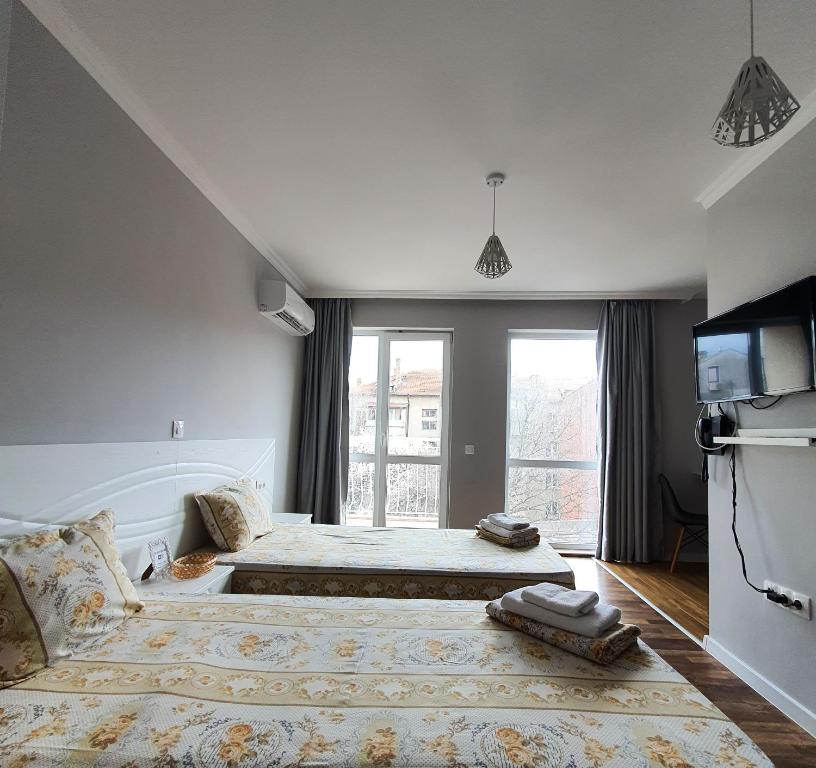 a bedroom with two beds and a large window at Студио High Class in Burgas