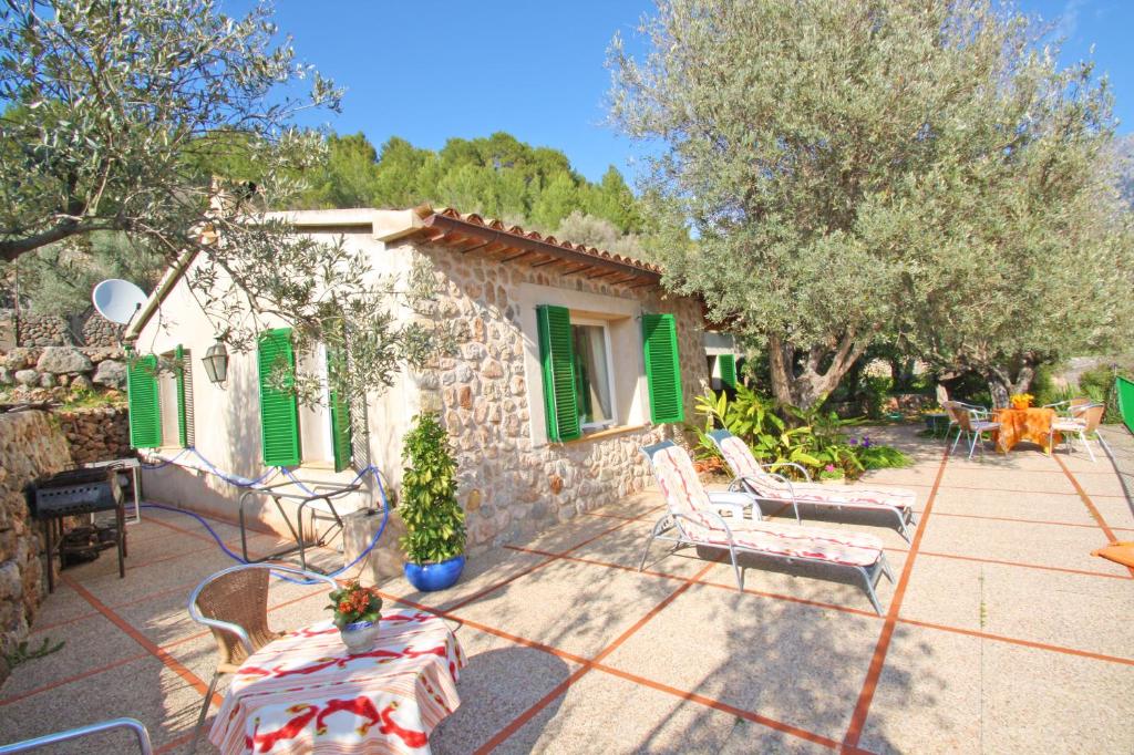 uma casa de pedra com persianas verdes e um pátio em Can Bac em Sóller