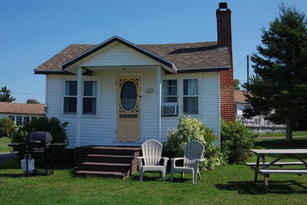 two chairs and a table in front of a house at Shining Waters - Ingleside Cottages in Cavendish