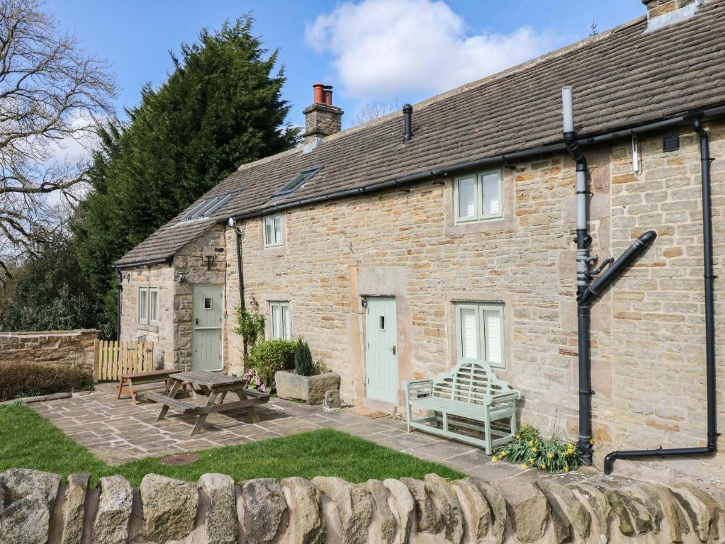 a brick house with a patio and a picnic table at Broadwood Farm in Hathersage