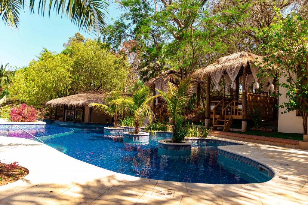 a swimming pool with palm trees and a house at Los Lagos Resort Hotel in Capiatá