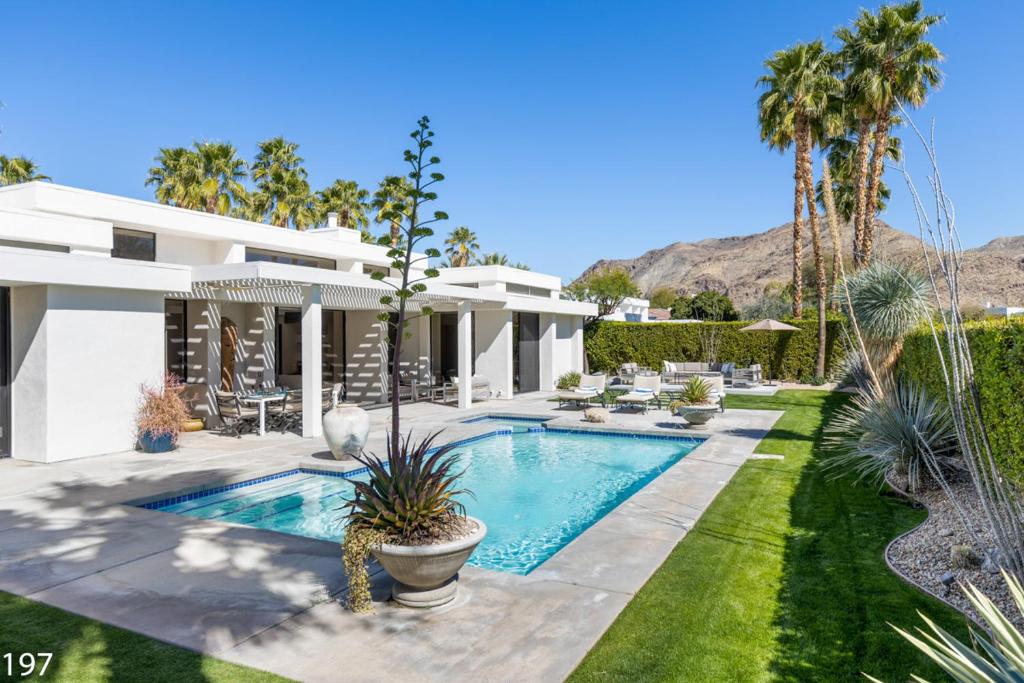 a house with a swimming pool and palm trees at Contemporary Dreams in Palm Springs