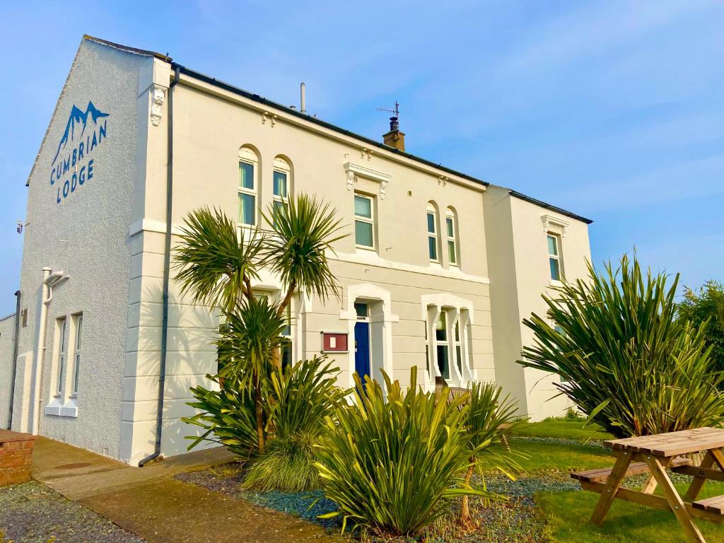 a white building with palm trees in front of it at Cumbrian Lodge in Seascale