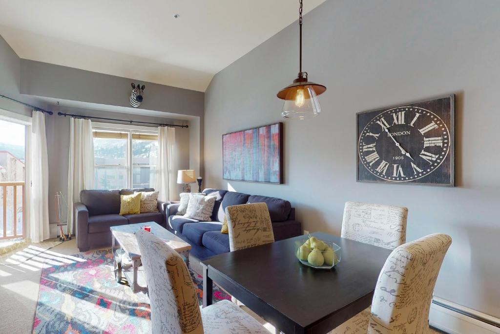 a living room with a table and a clock on the wall at Copper Springs Lodge 430 in Copper Mountain