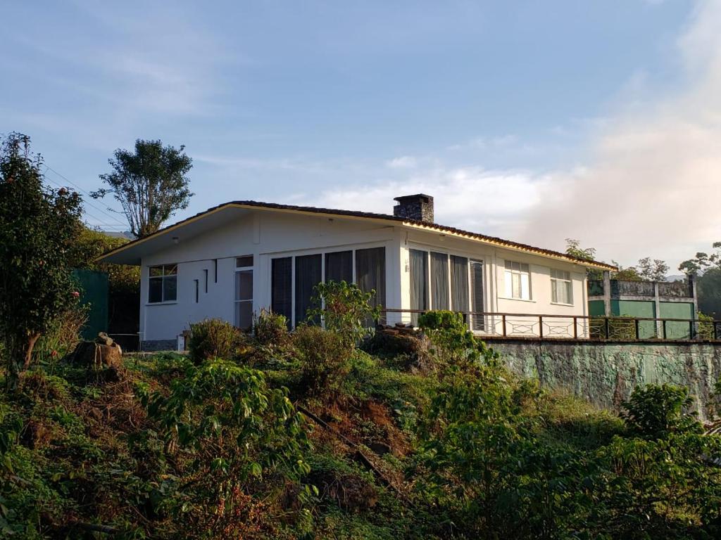 a white house sitting on top of a hill at Cabañas y Camping Aroma in Xicotepec de Juárez