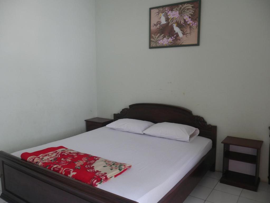 a bedroom with a bed with white sheets and a picture on the wall at Hotel Garuda near Alun Alun Banjarnegara Mitra RedDoorz in Wonosobo