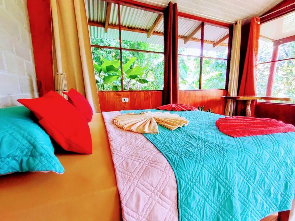 a bedroom with a bed with colorful pillows on it at The Sunset Tucano Lodge in Drake