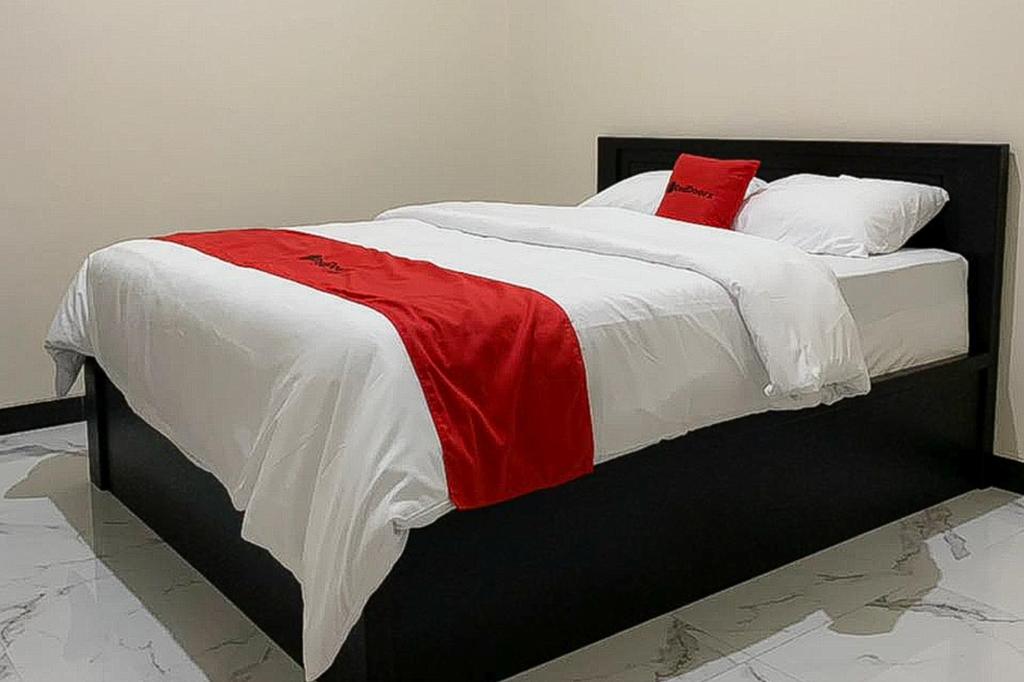1 cama con almohadas y mantas rojas y blancas en RedDoorz Syariah near Kawasan Simpang Lima Pati en Pati