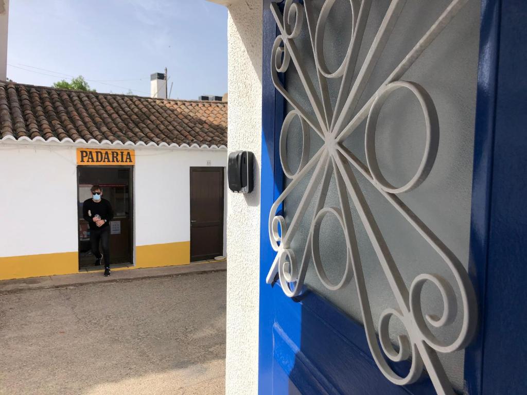 una puerta a un edificio con un hombre entrando en él en Casa do Viajante - Suite en Zambujeira do Mar