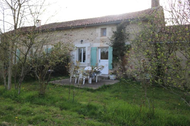 a house with a table and chairs in front of it at Gîte de caractère in Le Vigeant