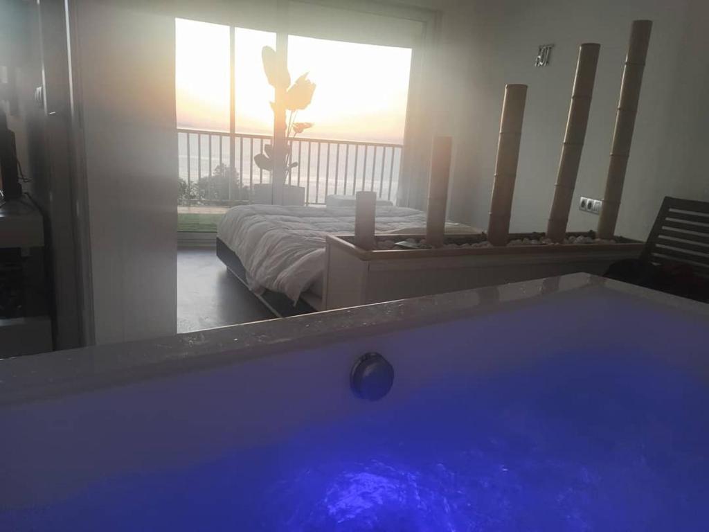 Una bañera en una habitación con cama y una persona en la ventana en Exclusivo Apartamento Spa privado frente el mar, en Miami Platja