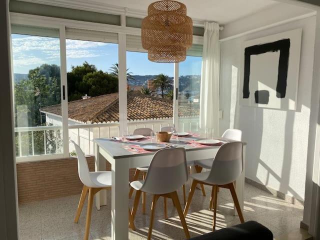 een eetkamer met een tafel en stoelen en een groot raam bij Apartamento RosarioyEmma - Primera línea de playa con vista mar in Jávea