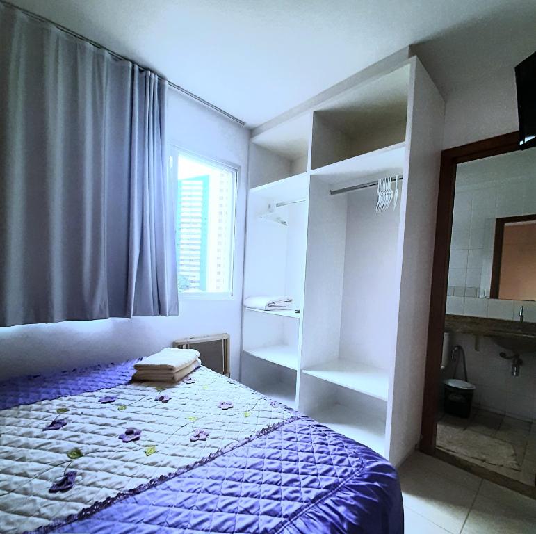 a bedroom with a bed and a window and a mirror at Flats Bueno em Goiânia in Goiânia