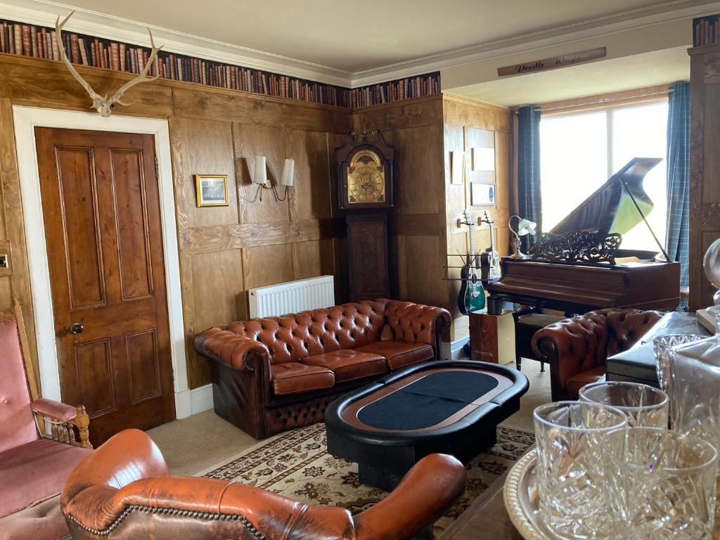 a living room with leather furniture and a piano at Shorelands B&B in Kirkwall