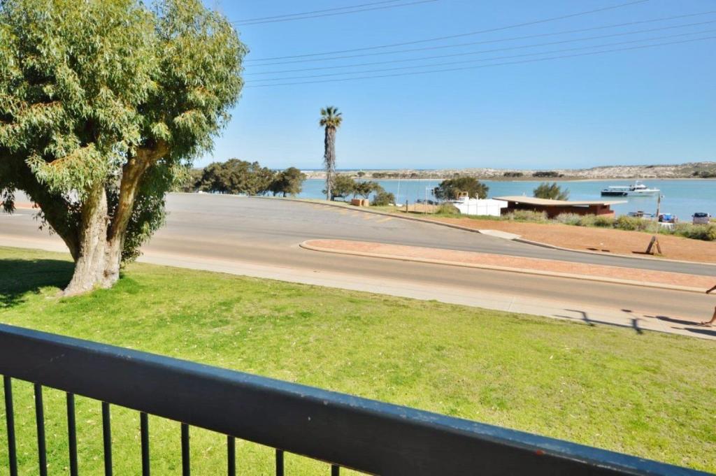 a black fence with a tree and a street at Riverview Holiday Apartment 12 - Kalbarri WA in Kalbarri