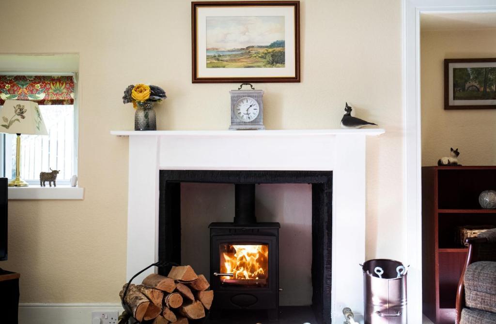 a living room with a fireplace with a fire at Mill Cottage in Forres