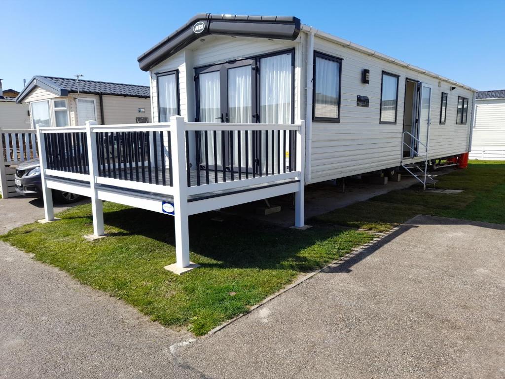 a tiny house with a white railing on the grass at The Beaches - New Beach in Dymchurch