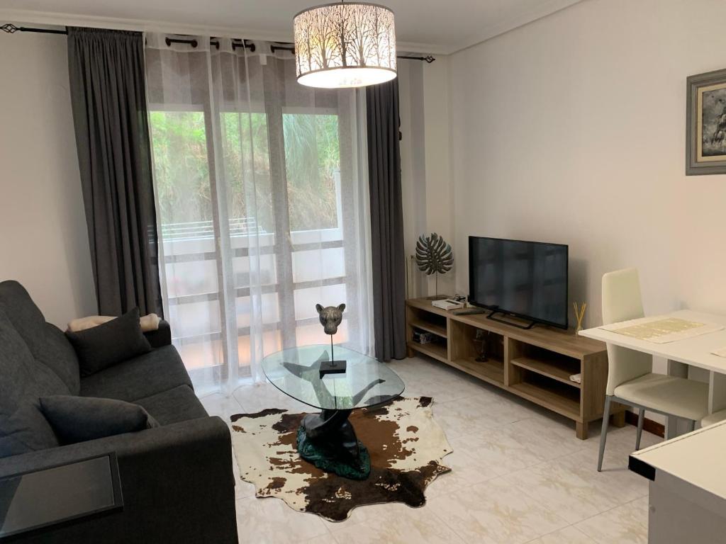 sala de estar con sofá, mesa y TV en Apartamento la Ribera en Suances