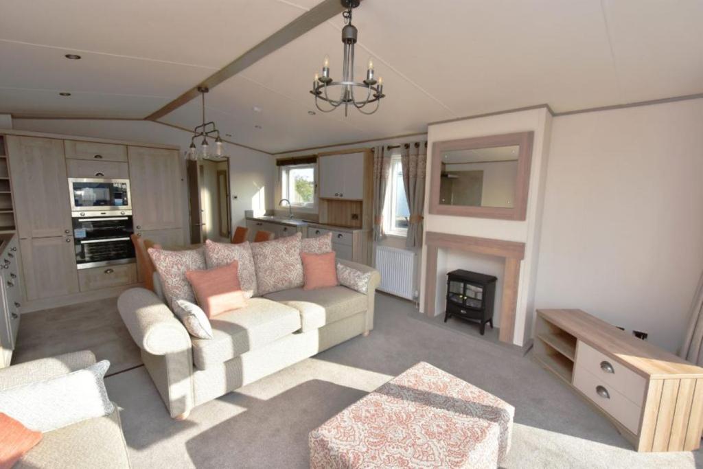 sala de estar con sofá y chimenea en Bluebell Lodge, en South Cerney