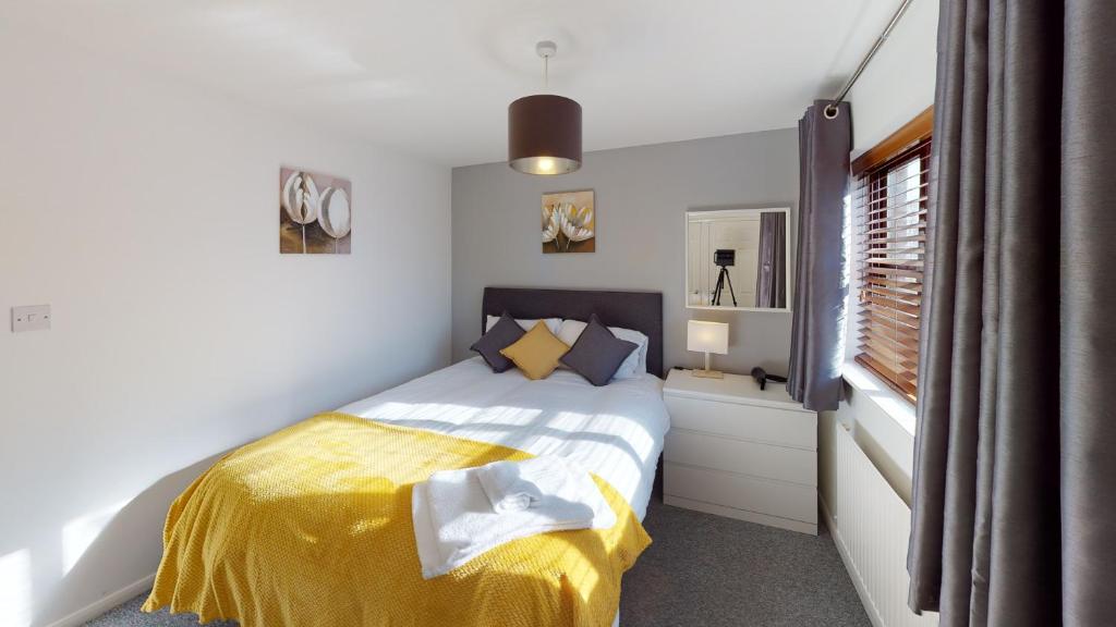 a bedroom with a bed with a yellow blanket and a window at Marina House in Hull
