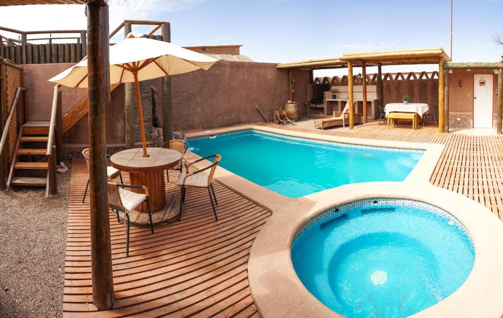 a swimming pool with a table and an umbrella at La Casa de José in San Pedro de Atacama