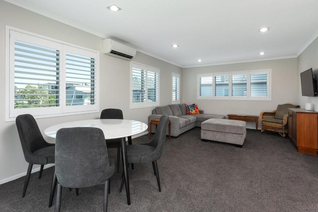 a living room with a table and chairs and a couch at Modern Marine Parade Apartment in Mount Maunganui