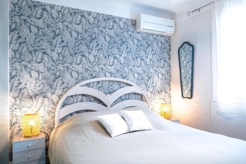 a bedroom with a white bed with a blue and white wallpaper at Appartement Barcares Village VUE MER in Le Barcarès