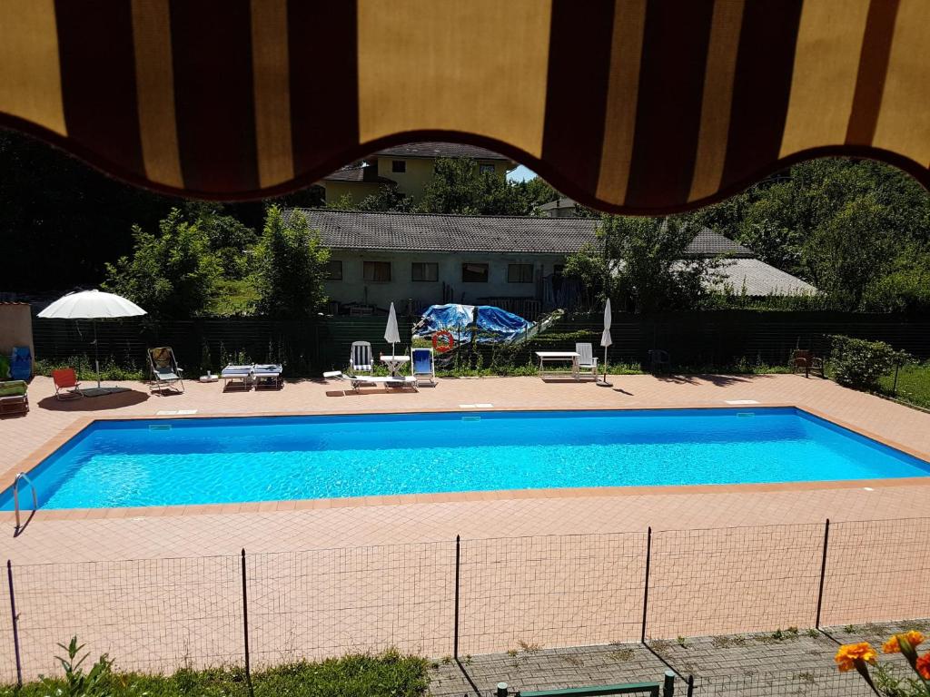 ein großer blauer Pool mit Stühlen und Sonnenschirmen in der Unterkunft Appartamento con Piscina in Lunigiana in Arpiola