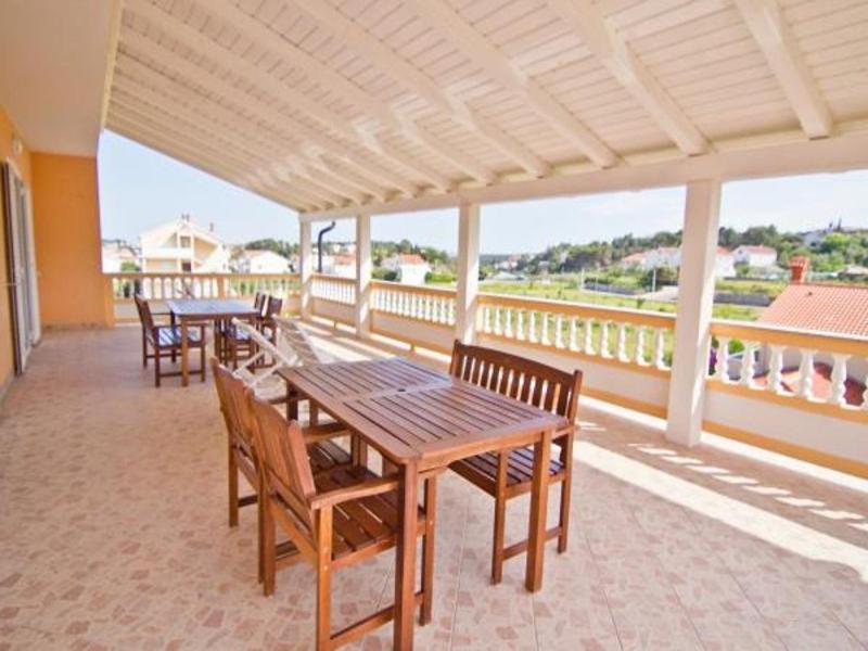 d'une terrasse avec des tables et des chaises en bois sur un balcon. dans l'établissement Apartments Spomenka - green paradise;, à Mundanije
