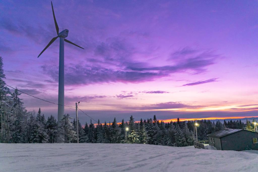 eine Windmühle auf einem verschneiten Hügel mit Sonnenuntergang in der Unterkunft The Inn at Bolton Valley in West Bolton