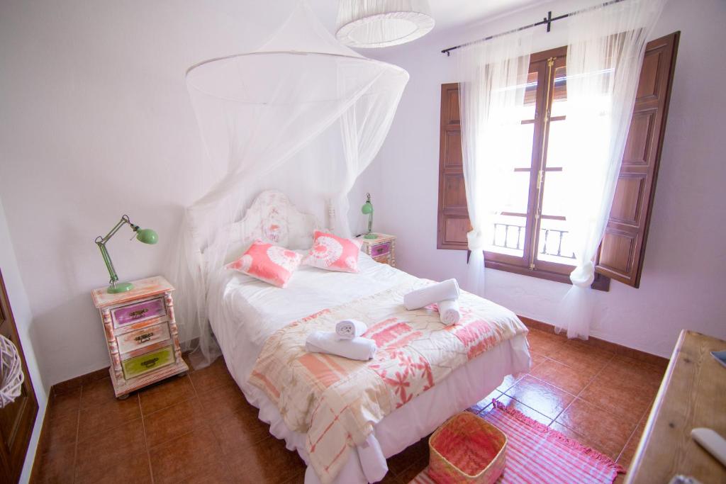 a bedroom with a bed with pink sheets and a window at Hotel Rural Inz-Almaraz in Jimera de Líbar