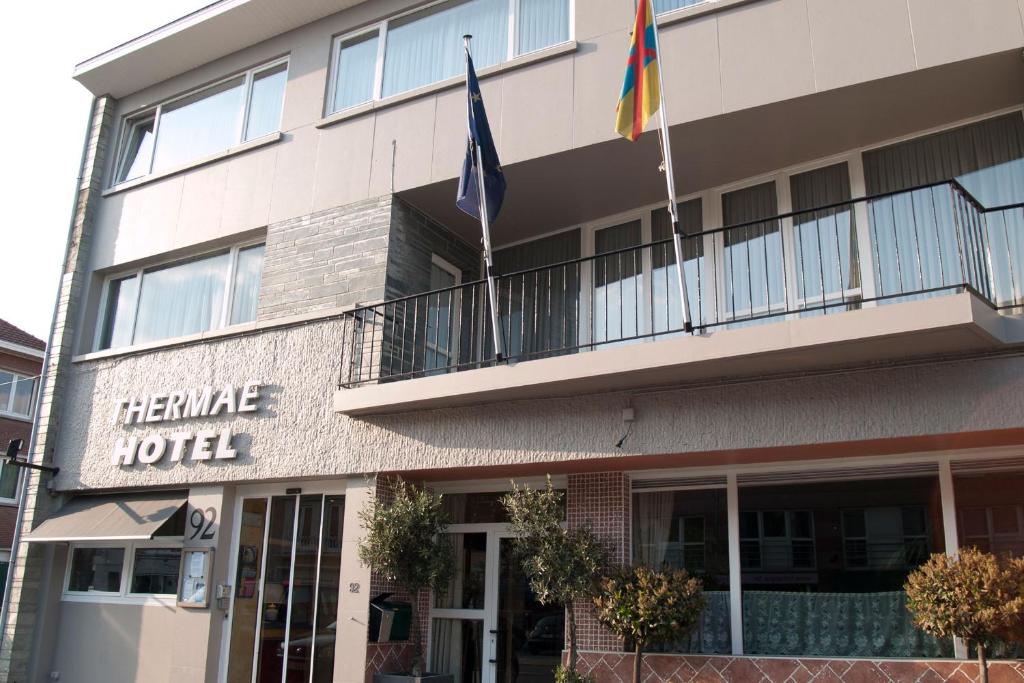 un hôtel avec deux drapeaux devant lui dans l'établissement Thermae Grimbergen Hotel, à Grimbergen