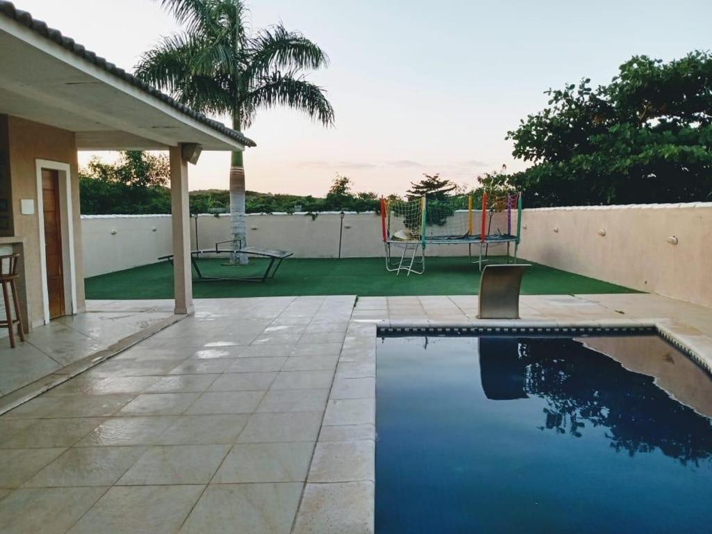 um quintal com uma piscina e um parque infantil em Casa Búzios - Temporada em Búzios