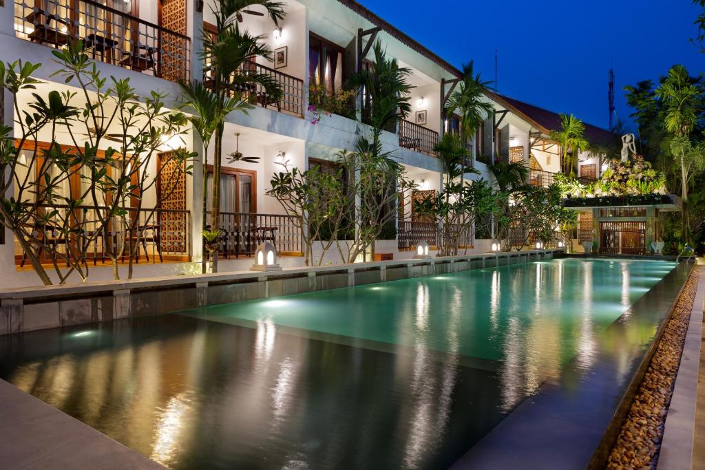a swimming pool in front of a building at night at Montra Nivesha Residence in Siem Reap