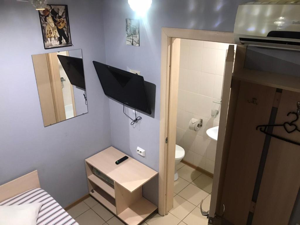 a small bathroom with a television on the wall at Hotel London in Chelyabinsk