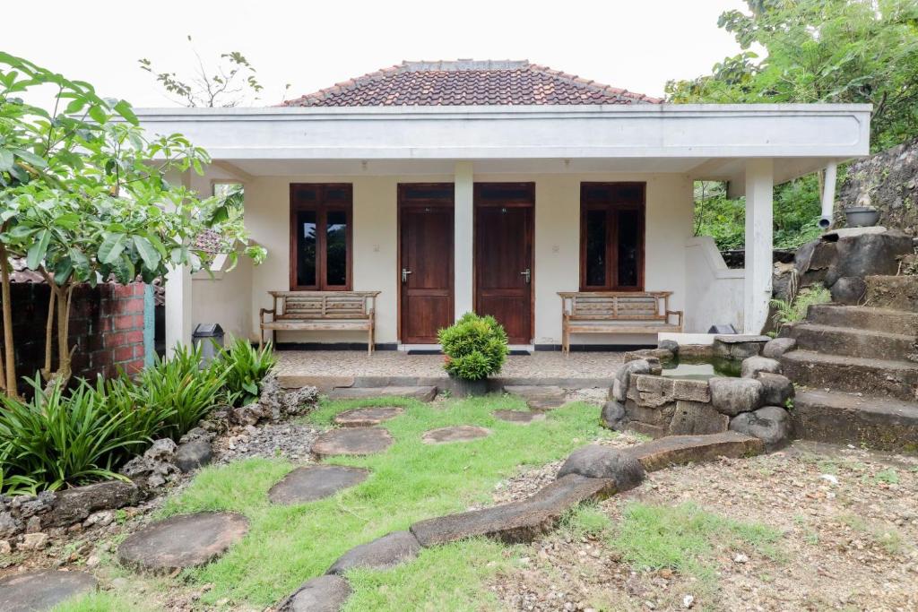 a small house with two benches in the yard at Rock Garden Homestay & Resto in Tepus