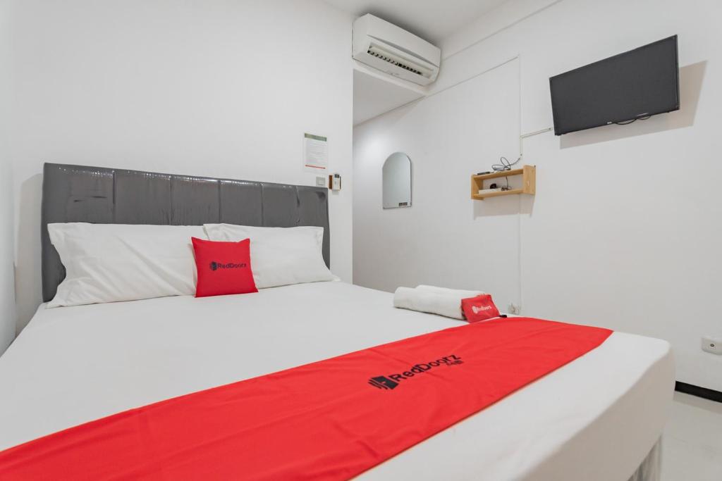 a bedroom with a red blanket on a bed at RedDoorz Syariah near Regol Park Bandung in Bandung
