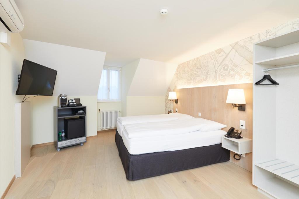 a bedroom with a bed and a flat screen tv at Kreuz Bern Modern City Hotel in Bern