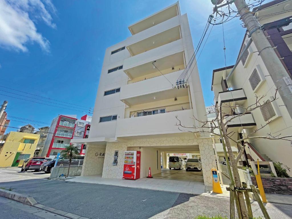 wysoki biały budynek z czerwoną stacją benzynową w obiekcie G-RATIS Omoromachi w mieście Naha