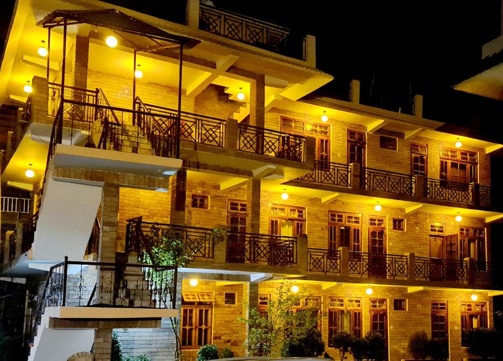 a large apartment building with a balcony at night at BabyLon Resort in Kasol
