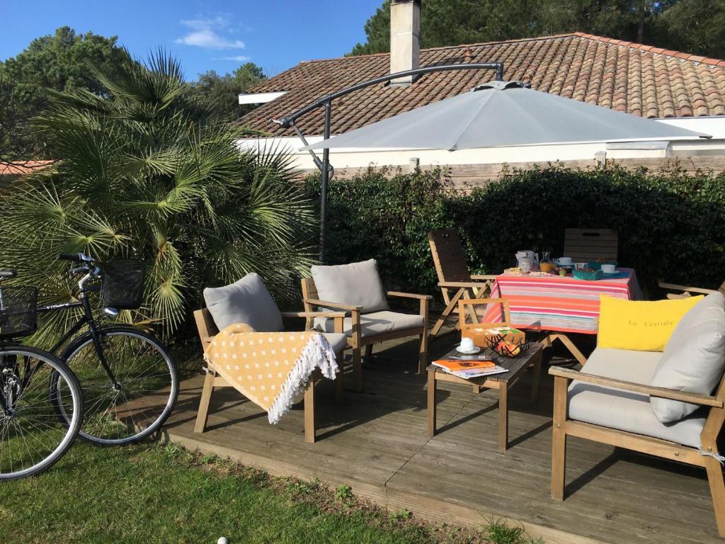 d'une terrasse avec des chaises, une table et un vélo. dans l'établissement Aux Sources d'Hossegor, à Hossegor