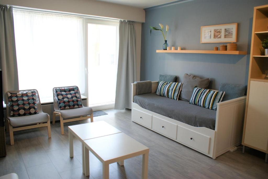 een woonkamer met een bank en 2 stoelen bij Sea Side in Oostende