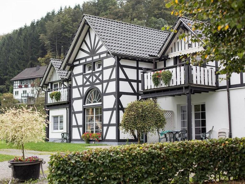 a black and white building with a balcony and tables at Gerwenshof in Schmallenberg
