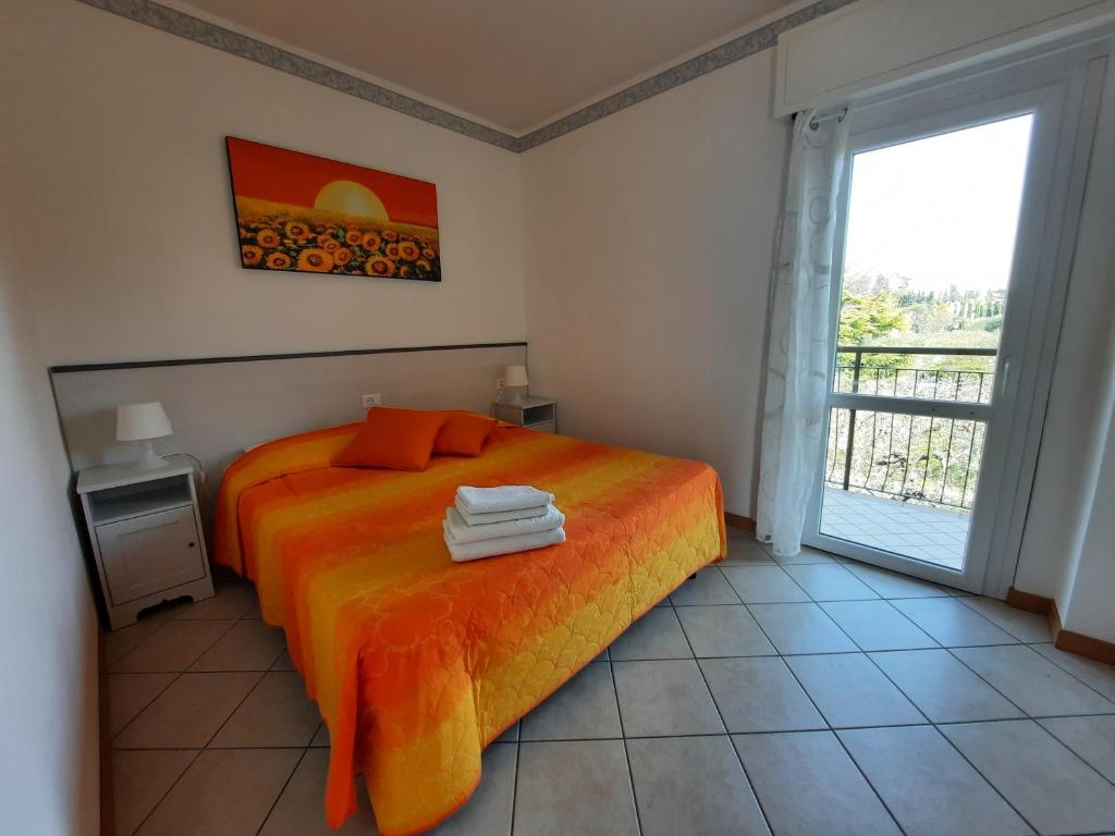 a bedroom with a bed with orange sheets and a window at Villa Mayoti B&B in Manerba del Garda