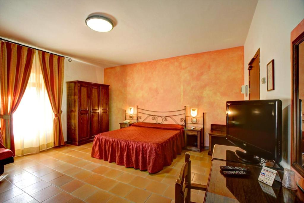 a bedroom with a bed and a flat screen tv at Hotel Residence Villa Rioddi in Volterra